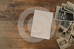 Stack of old vintage monochrome photographs on photographic paper on natural wood background, concept of genealogy, memory of photo