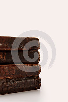 Stack of old worn shabby Jewish books in leather binding on white background with reflection. Closeup. Selective focus