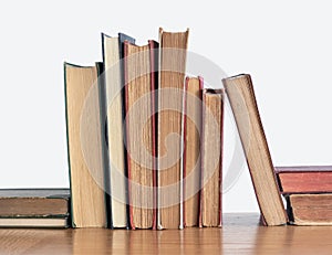 Stack of old yellowed books on a wooden shelf