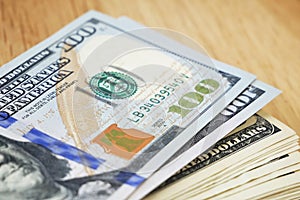 Stack of one hundred dollar bills on wooden background, closeup