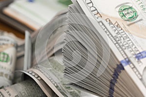 Stack of one hundred dollar bills on a wooden table