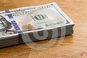 Stack of one hundred dollar bills on a wooden table