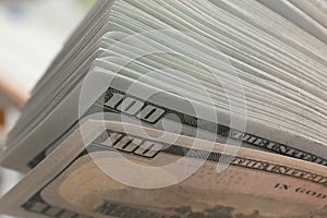 Stack of one hundred dollar bills on a wooden table