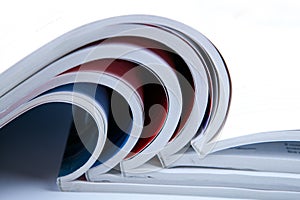 Stack of open glossy magazines on white background