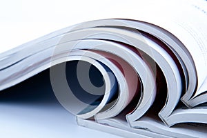 Stack of open glossy magazines on white background