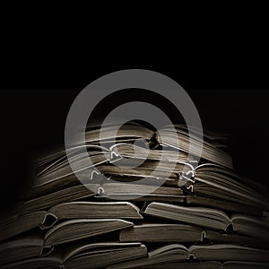 Stack of open old books in black background