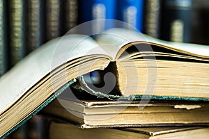 Stack of opened old books on wood table, volumes in the background, reading, education concept