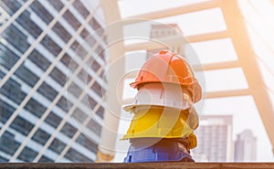 Stack of orange, white, yellow and blue hard safety helmet on floor in construction site. Industry safety health concept