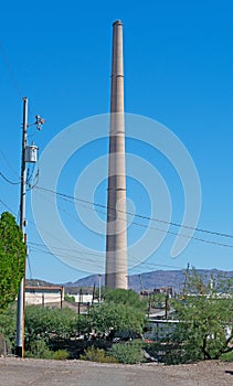 Stack from an ore smelter against the blue sky on the edge of town