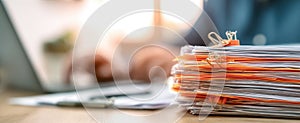 The stack of organized paperwork beside a laptop in a professional workspace..AI generated image