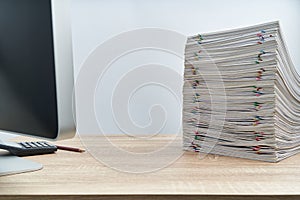 Stack of overload paperwork report and computer on wooden table