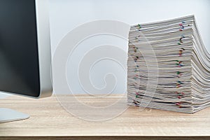 Stack of overload paperwork report and computer on wooden table