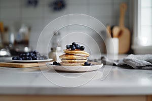 A stack of pancakes with blueberries on top of a white plate