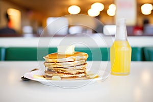 stack of pancakes with butter and syrup in a diner setting