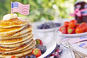 Stack of pancakes with fresh fruit, syrup and butter