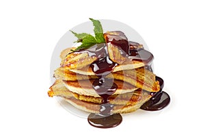 Stack of pancakes with fried banana, mint leaf and chocolate syrup on white
