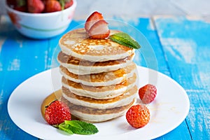 Stack of pancakes fritters with strawberries and honey on a pl