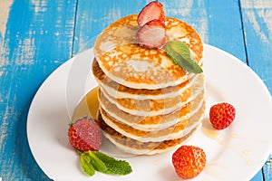 Stack of pancakes fritters with strawberries and honey on a pl