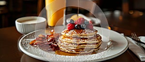 A stack of pancakes generously topped with fresh berries and drizzled with syrup, creating a delicious and indulgent