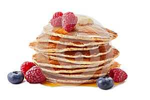 Stack of pancakes with maple syrup and fresh berries on white