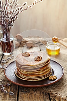 Stack of pancakes with nuts on vintage wooden table