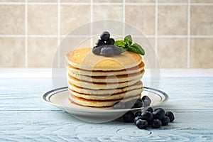 Stack of pancakes with pile of blueberries on plate