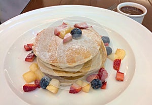 stack of pancakes served with pieces of fresh fruits