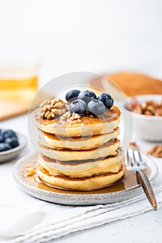 Stack of pancakes served with syrup, blueberries and walnuts