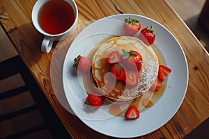 A stack of pancakes with strawberries and syrup on top of a white plate
