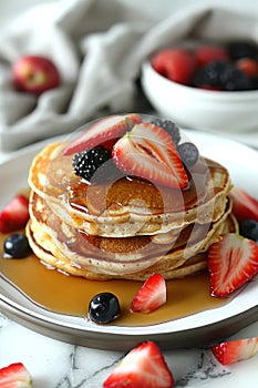 A stack of pancakes with syrup, strawberries on a plate