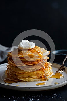 Stack of pancakes with syrup and whipped cream
