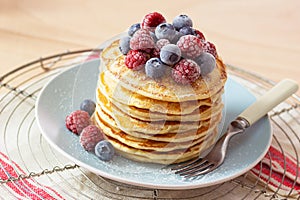 Stack of Pancakes Topped with Frozen Berries and Powdered Sugar