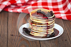 Stack of pancakes white plate with cherry jam, red napkin, brow