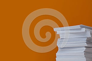 Stack of paper sheets on orange background. Space for text
