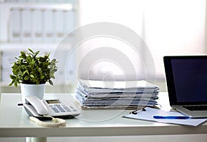 A stack of papers on the desk with a computer photo