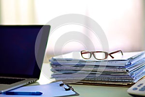 Stack of papers on the desk with computer