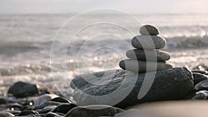 Stack of pebble stones, pyramid stands in front of waves coming to the beach.