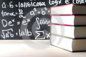 Stack and pile of books in front of a blackboard in school.