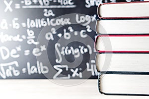Stack and pile of books in front of a blackboard in school.