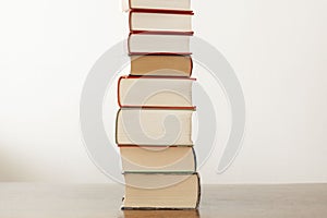 Stack of piled books rest on a wooden table with copy space for your text