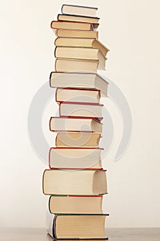 Stack of piled books rest on a wooden table with copy space for your text