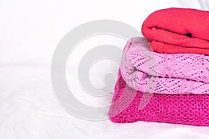 Stack of pink sweaters on white.