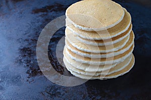 Stack of plain pancakes on dark background