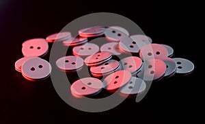 Stack of plastic weaving buttons on black surface