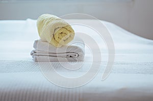 Stack of plush hotel clean soft towels White,Blue,Yellow towel on bed decoration in bedroom