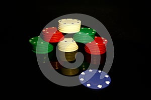 Stack of poker chips with a blue chip in front and reflections isolated on black