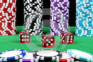 Stack of Poker chips on a green gaming poker table with poker dice at the casino. Playing a game with dice. Casino dice Concept