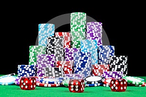 Stack of Poker chips on a green gaming poker table with poker dice at the casino. Playing a game with dice. Casino dice