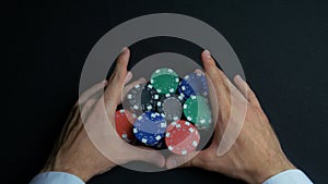 Stack of poker chips and two hands on table. Closeup of poker chips in stacks on green felt card table surface. Poker