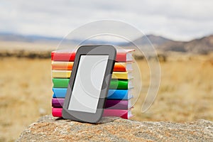 Stack of printed books with electronic book reader